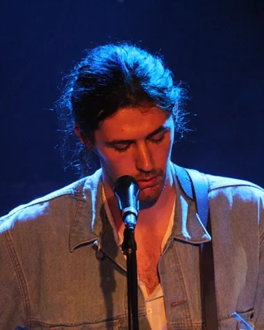 Hozier performing live onstage with a guitar and microphone