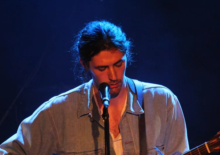Hozier performing live onstage with a guitar and microphone